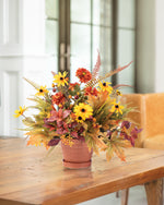 Black-Eyed Susan & Rosehip Faux Flower Centerpiece arranged in a 5” ceramic pot on a wooden table.