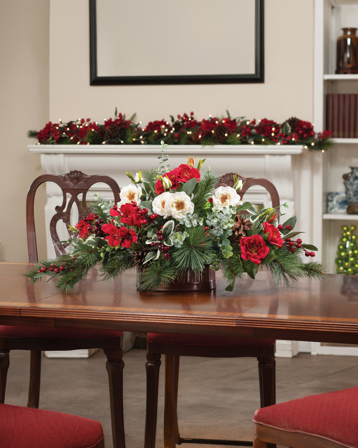 Large Holly, Pine & Berries Faux Holiday Centerpiece set on a wooden table with Christmas decorations surrounding.