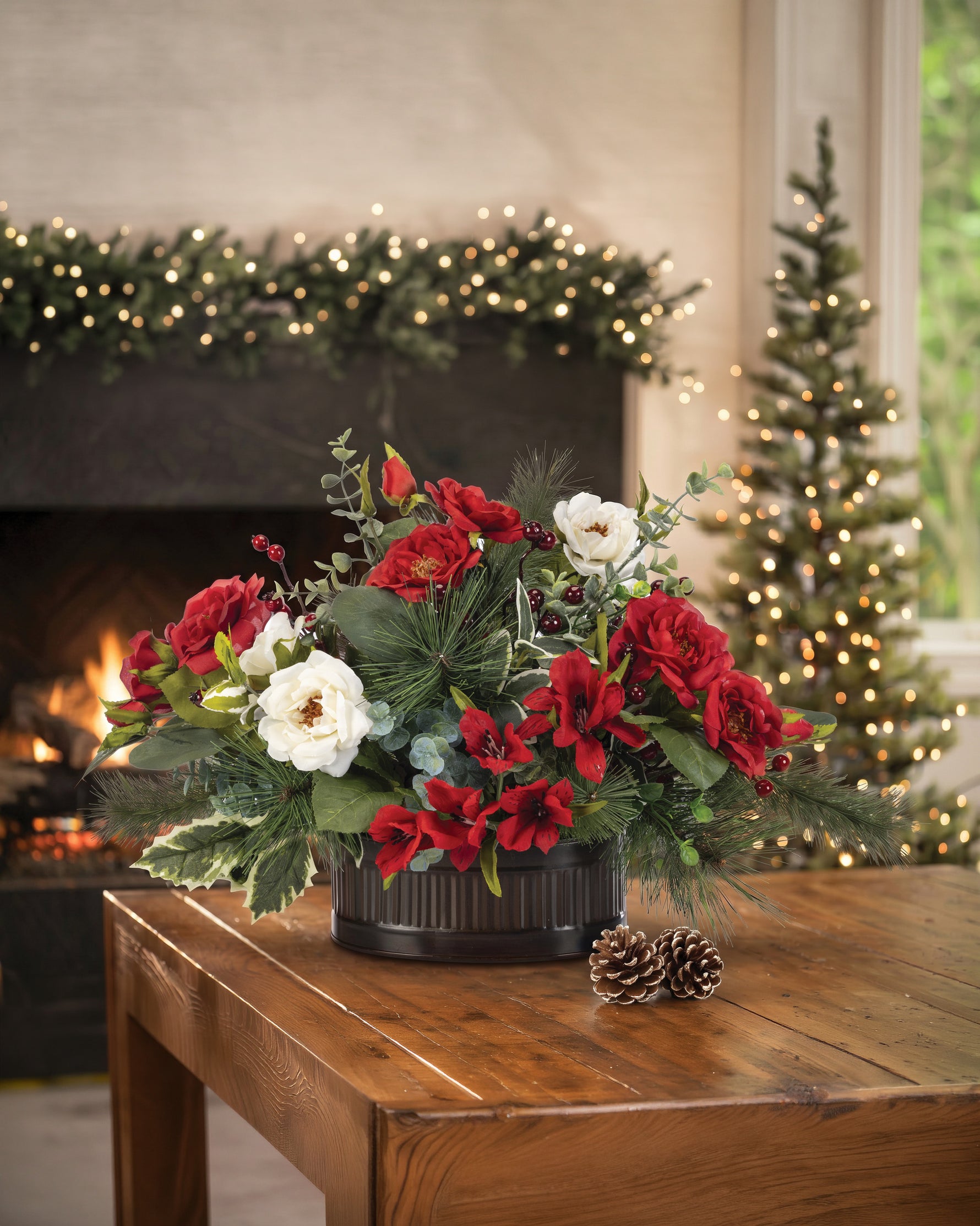 Medium Holly, Pine & Berries Artificial Holiday Centerpiece, set in Oval Metal Container and displayed on a wooden table with Christmas decorations.
