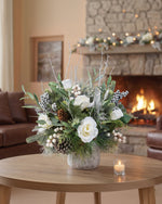 Winter White & Silver Artificial Holiday Centerpiece, set in Tree Embossed Pot, in front of a fireplace.
